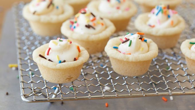 cupcakes with white frosting and sprinkles on a cooling rack