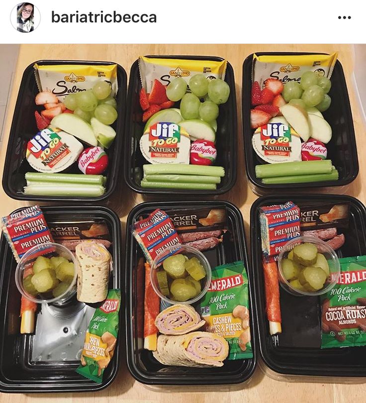 four plastic trays filled with food on top of a wooden table next to each other