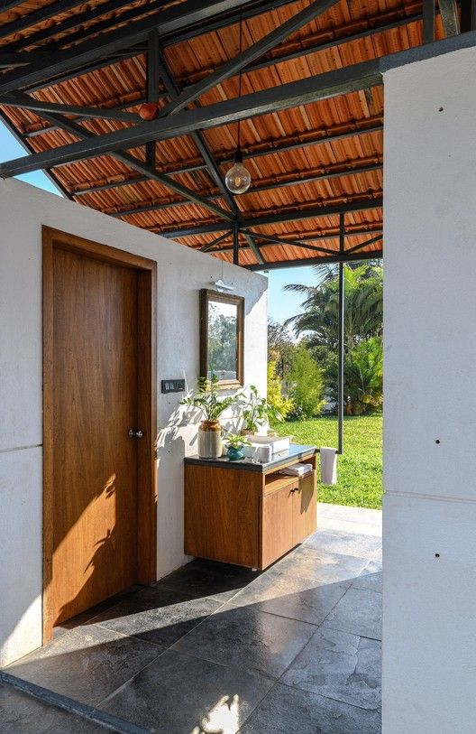 an outdoor bathroom with wooden doors and tiled flooring, surrounded by greenery in the background