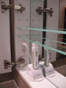 two electric toothbrushes sitting on top of a counter in front of a mirror