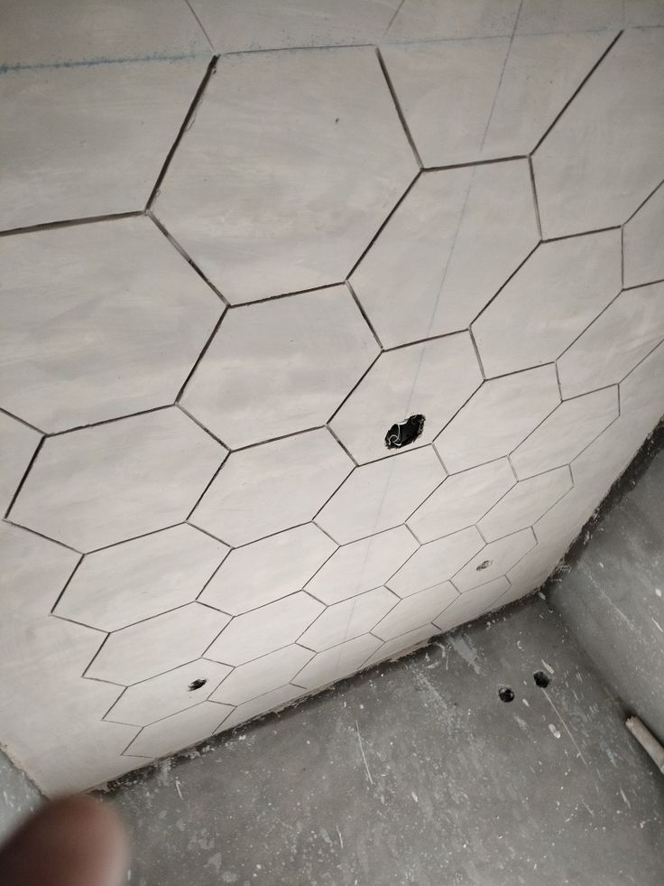 the corner of a bathroom with a hole in the floor and tile on the wall