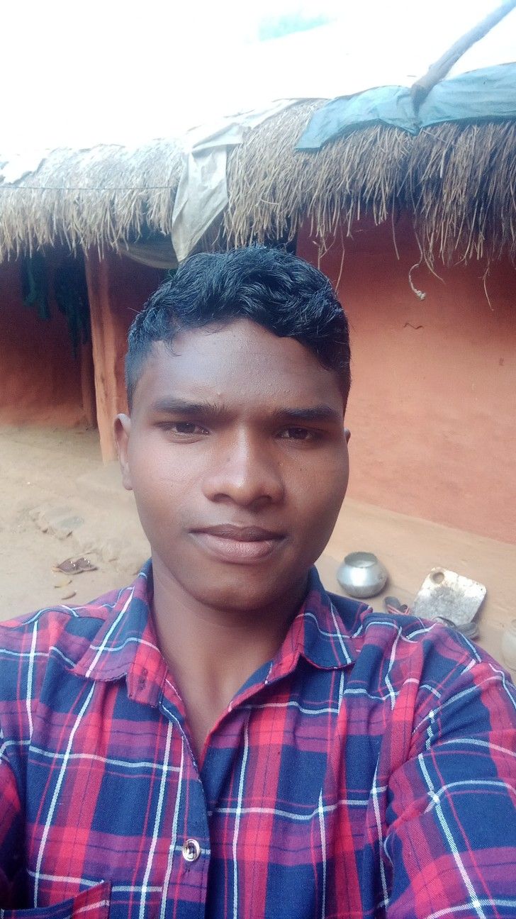 a man standing in front of a hut with thatched roof and grass on the ground