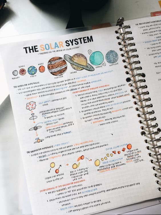 an open spiral notebook with the solar system written in it on top of a table