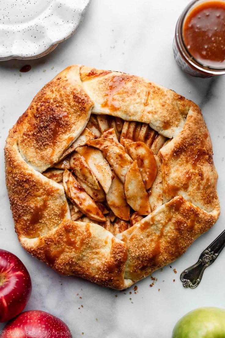 an apple pie with sliced apples next to it