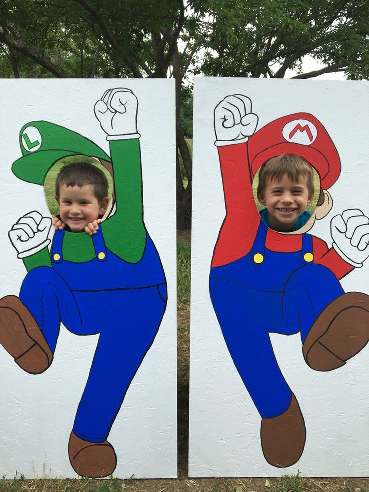 two cardboard cutouts of children in mario and luigi costumes, with trees in the background