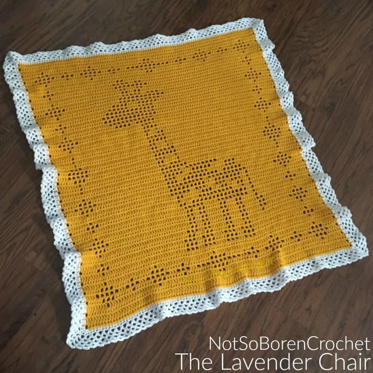 a yellow crocheted blanket on the floor with a giraffe design in it