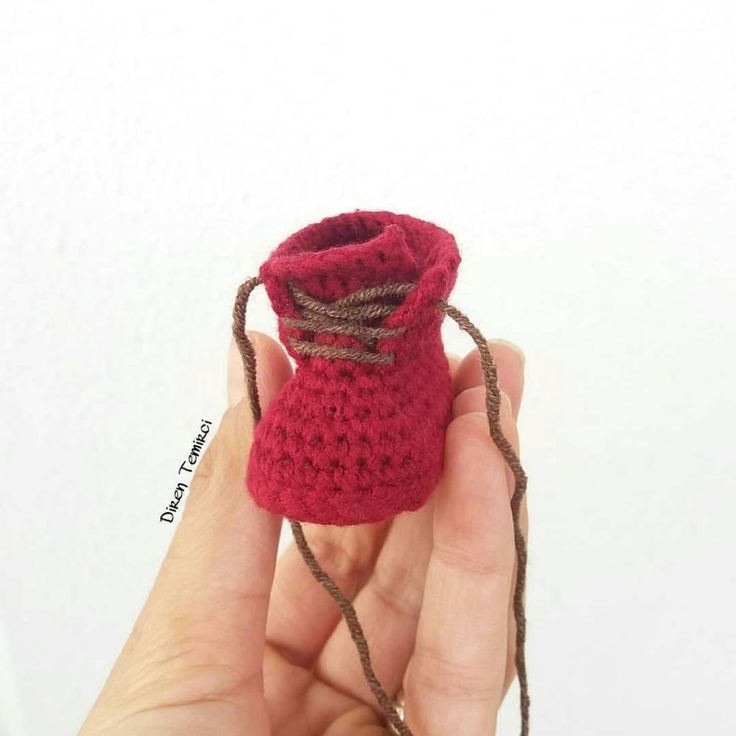 a hand holding a small crocheted bag with twine around the top and bottom