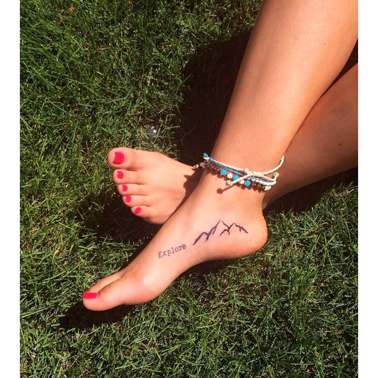 a woman's foot with the word explore written on it and a mountain tattoo