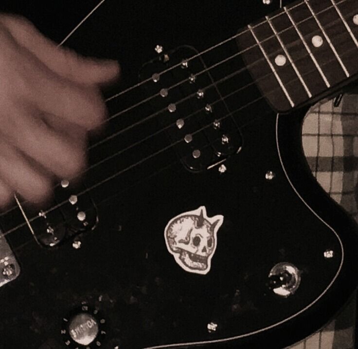 a person playing an electric guitar with a skull sticker on the top of it