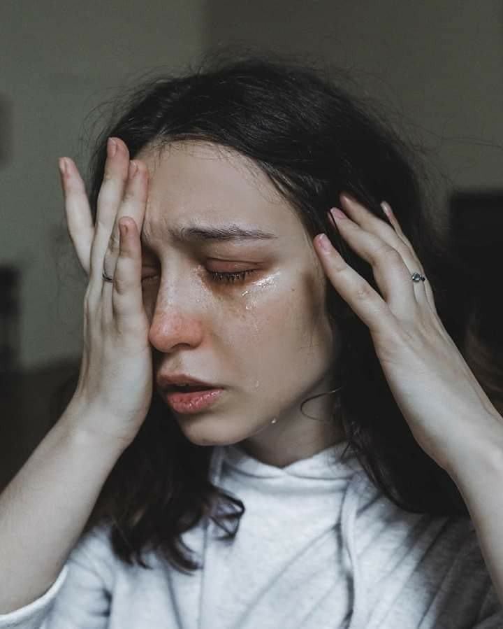 a woman holding her hands to her face with tears all over her cheeks and eyes