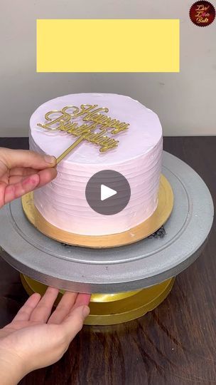 someone is decorating a pink cake with gold decorations