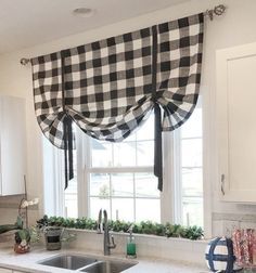 a kitchen with white cabinets and black and white checkered valance over the sink