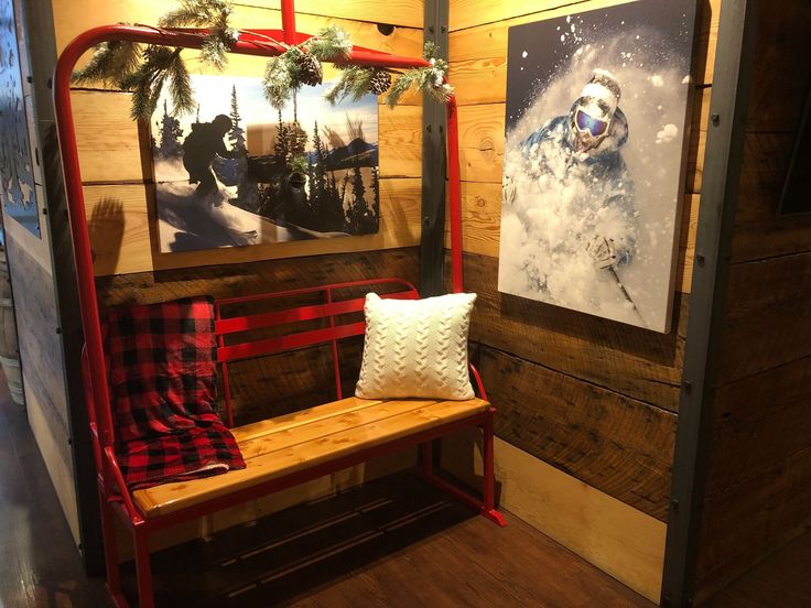 a wooden bench sitting in front of a wall with pictures on it and a snowboard hanging from the ceiling