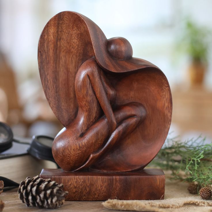 a wooden sculpture sitting on top of a table next to a pine cone and scissors