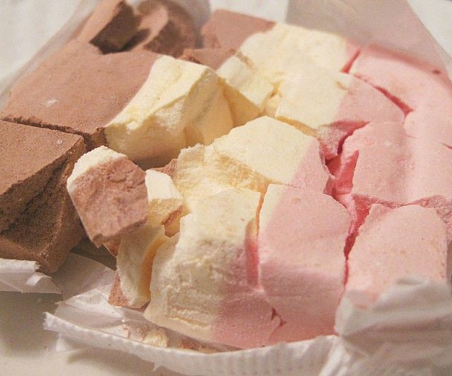 there is a white plate with pink and yellow marshmallows on it,