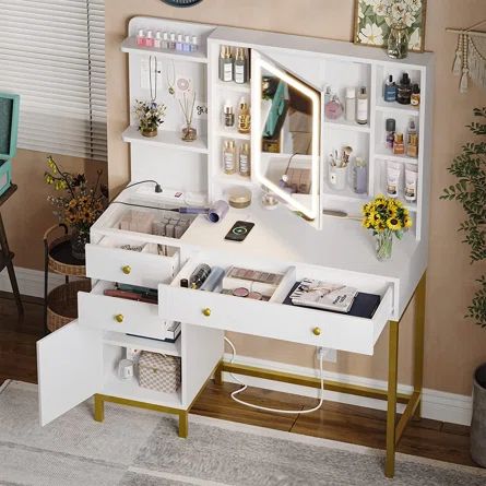 a white desk with lots of drawers under a mirror and some flowers on the table