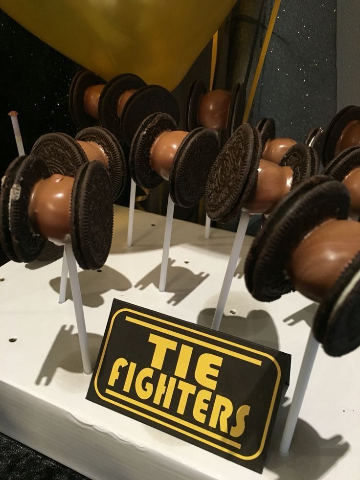 there are some cookies and oreo pops on the cake plate with stickers that say tie fighters