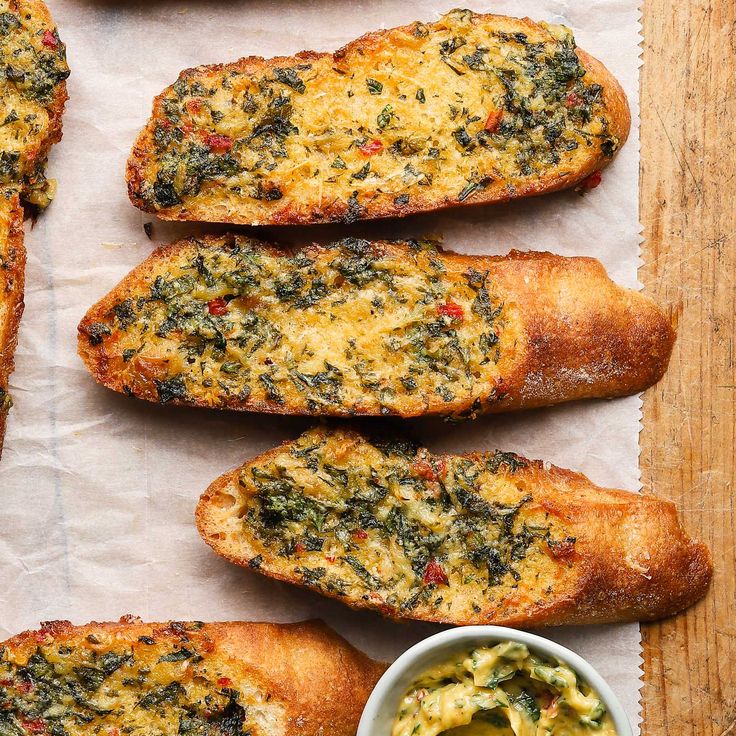 bread with spinach and cheese on it next to a small bowl of pesto sauce