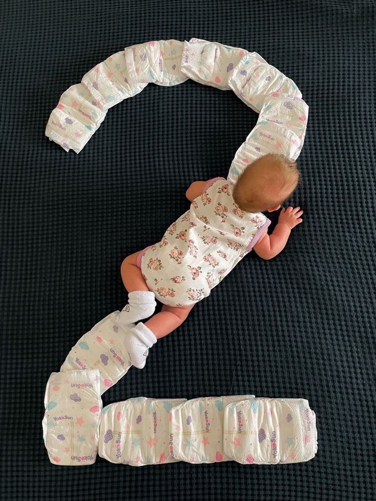 a baby is laying on the floor next to two diapers that are shaped like numbers