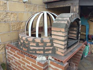 an outdoor brick oven built into the side of a building with bricks on it's sides