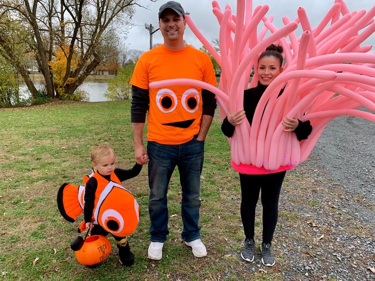 two adults and a child are standing in front of an orange floater with fish on it