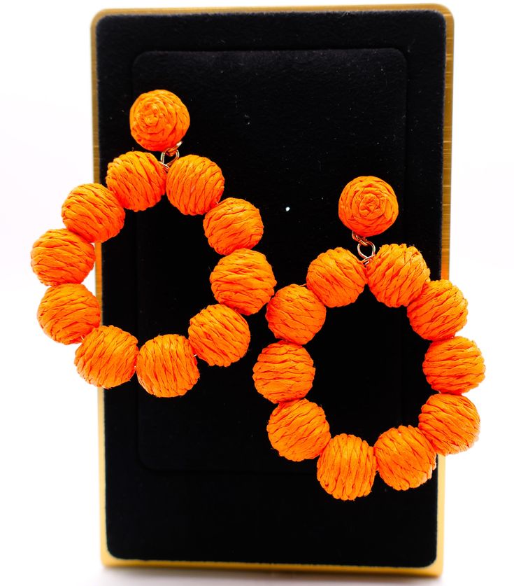 These striking hoop earrings capture the essence of a vibrant sunset on a tropical beach. Designed with bright orange straws that form the hoop, each earring is adorned with small orange balls for an extra touch of playful elegance. The result is a captivating statement piece that can instantly transform any outfit, making it stand out with a burst of color and lively charm. Length: 3 inches Care: Avoid contact with water and cosmetics, such as creams or perfumes. To restore the luster and shine Orange Drop Earrings For Beach, Orange Drop Earrings For The Beach, Orange Dangle Jewelry For Beach, Orange Round Earrings For Summer, Trendy Small Hoop Orange Jewelry, Orange Small Hoop Earrings For Summer, Adjustable Orange Hoop Earrings, Summer Orange Small Hoop Earrings, Trendy Small Hoop Orange Earrings