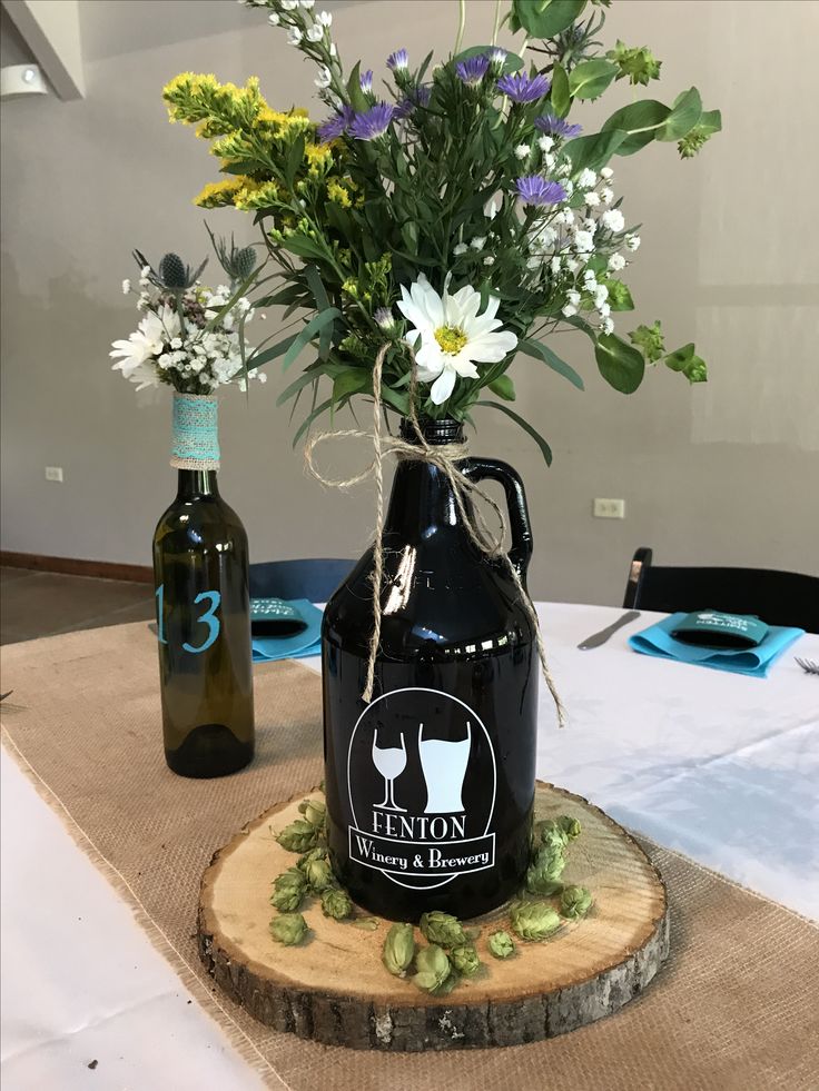 a vase with flowers in it sitting on a table next to two empty wine bottles