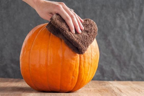 a person cleaning a pumpkin with a rag