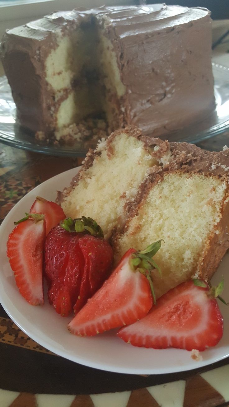 a slice of cake with strawberries on a plate next to another piece of cake