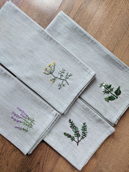 four linen napkins with embroidered flowers on them