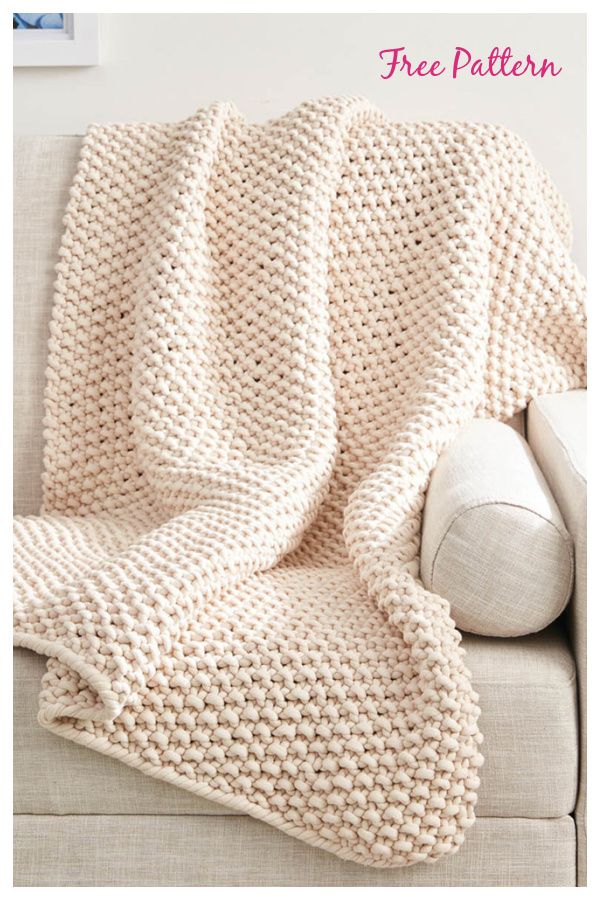 a white knitted blanket sitting on top of a couch next to a pillow and pillows