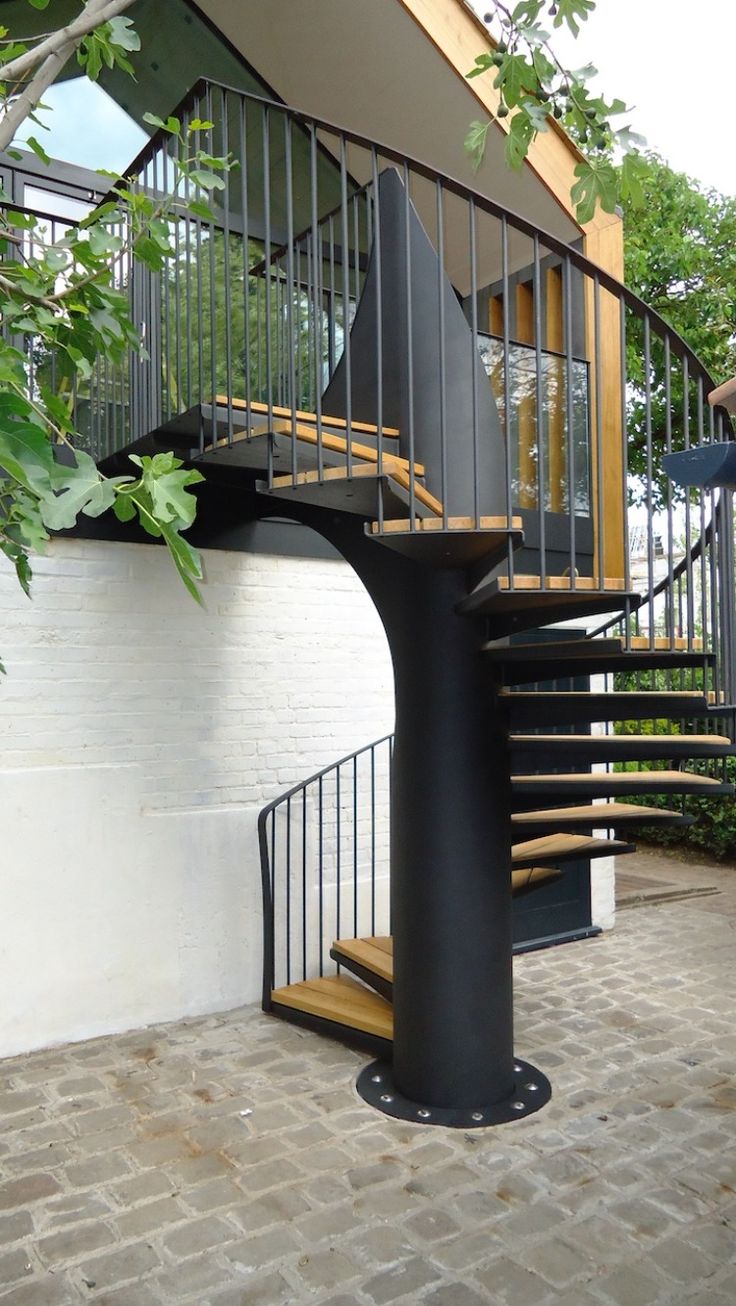 a black spiral staircase next to a white wall