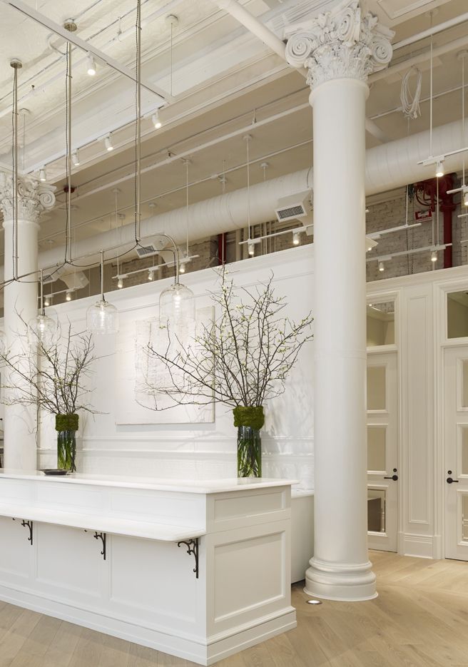 two vases with flowers are sitting on the counter in front of a white wall