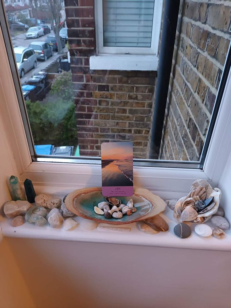 a window sill filled with seashells next to a sign that says welcome