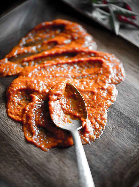 a spoon with sauce on it sitting on top of a cutting board