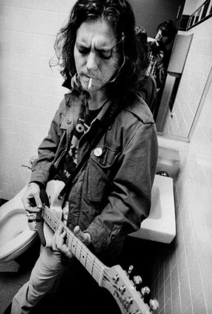 a person sitting on a toilet with a guitar