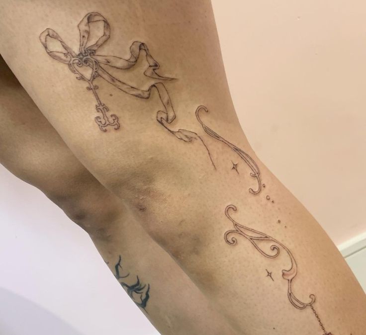 a woman's legs with tattoos on them and an anchor in the shape of a bow