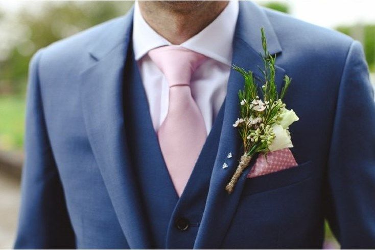 a man in a blue suit with a pink tie and flower boutonniere