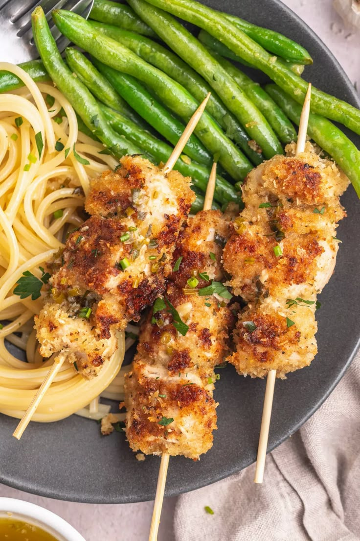 chicken skewers with pasta and green beans on a plate