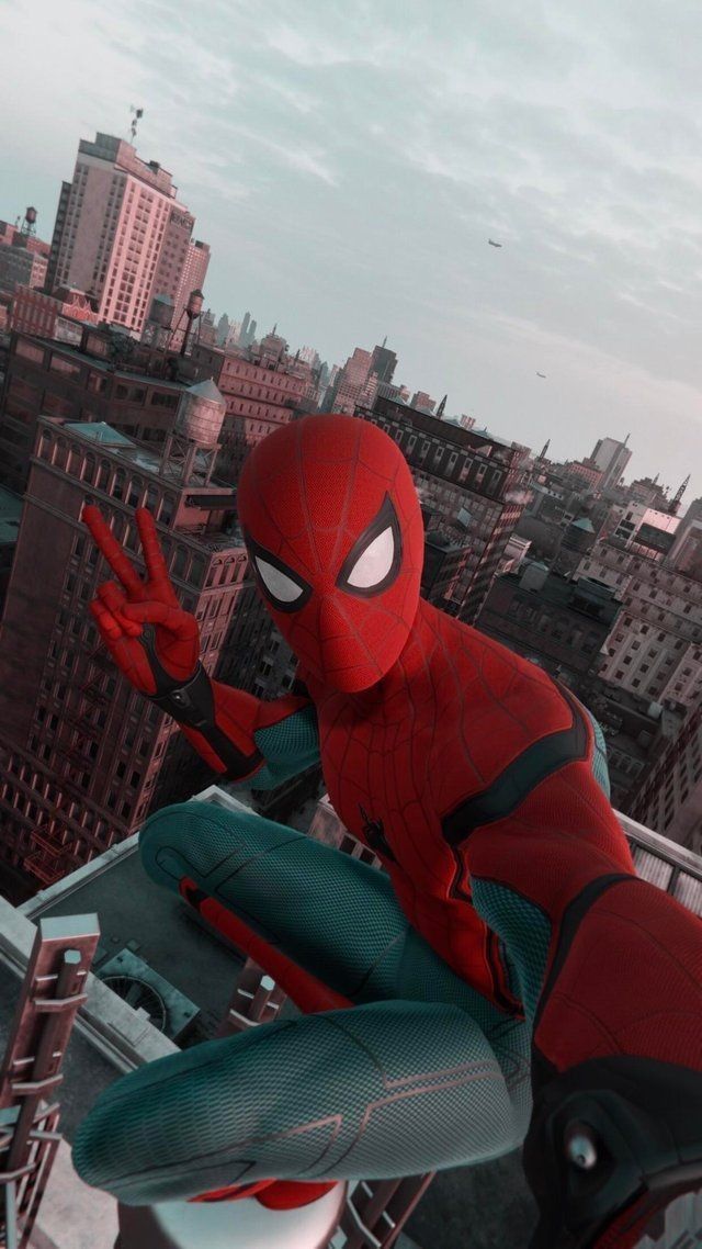 the spider - man is sitting on top of a building