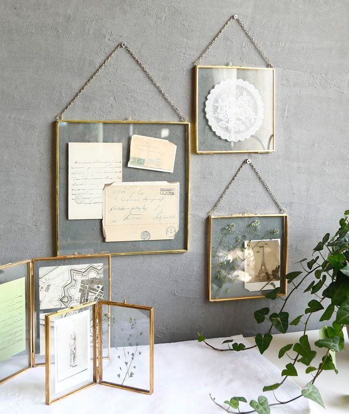 four framed photos hang on the wall above a white table with greenery in front of it