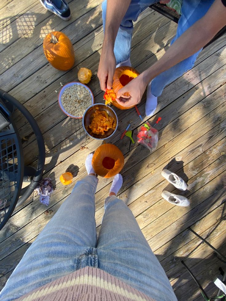 two people standing on a wooden deck with bowls of food in front of their feet