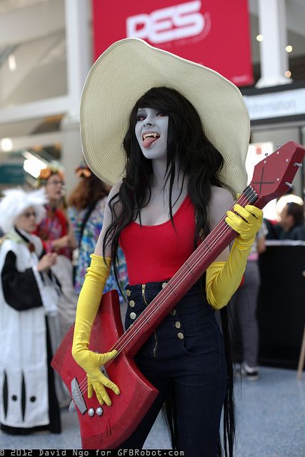 a woman dressed in costume holding a guitar and wearing a cowboy hat with yellow gloves