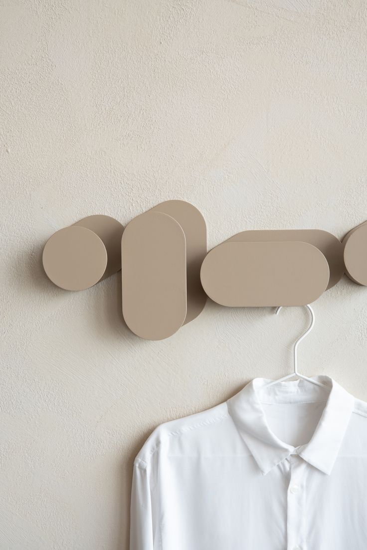 a white shirt is hanging on the wall next to a hanger with three circles