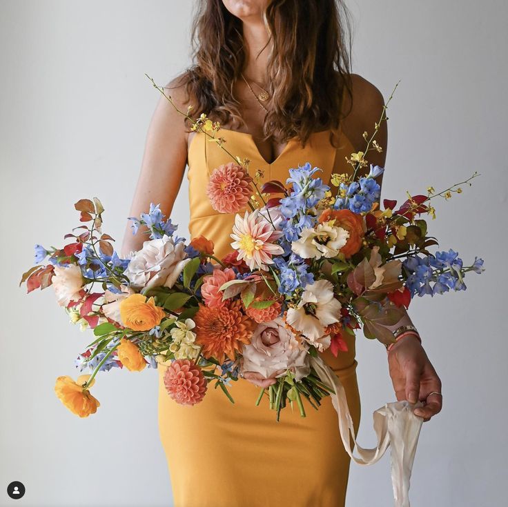 a woman in a yellow dress holding a bouquet of flowers