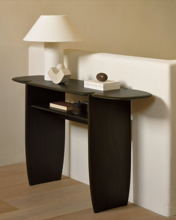 a table with a lamp on top of it next to a white wall and wooden floor