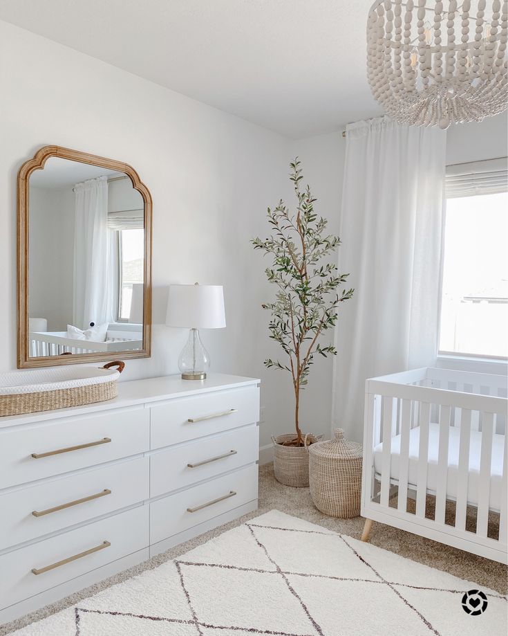 a baby's room with white furniture and a chandelier hanging from the ceiling