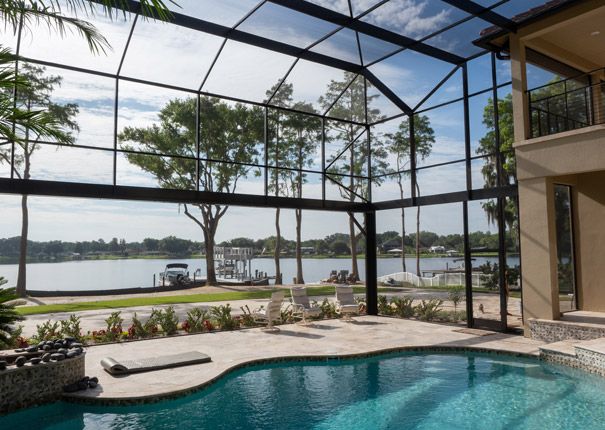 an indoor swimming pool surrounded by glass walls and palm trees in front of a lake