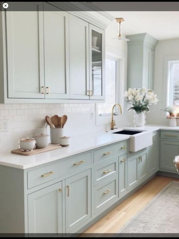 a kitchen filled with lots of white counter tops and wooden floors next to a window