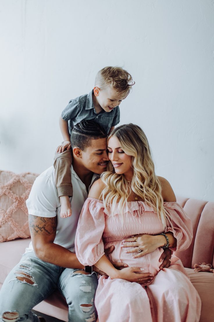 a man, woman and child sitting on a pink couch